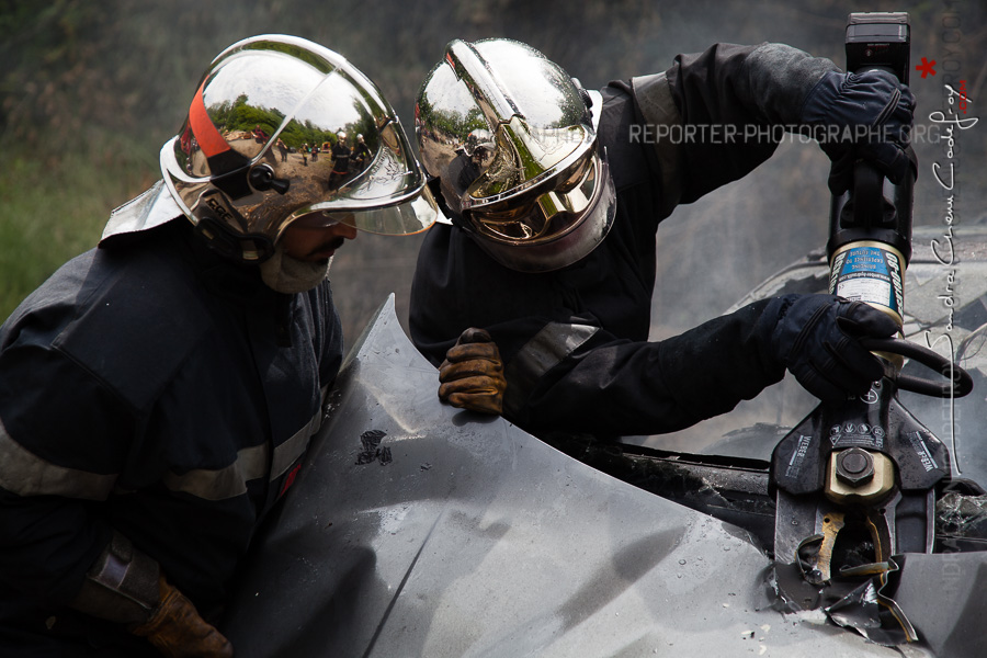 Sapeurs-pompiers de la Marne utilisant un outil de désincarcération pour accéder au moteur d'une voiture en feu [Ref:2116-13-0351]